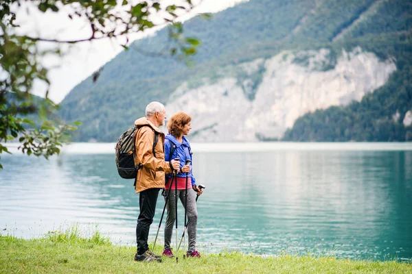 Een oudere gepensioneerde paar wandelaars bij het meer in de natuur. Kopieerruimte. — Stockfoto