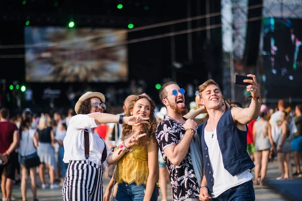 Grupp unga vänner med smartphone på sommarfestivalen, tar selfie. — Stockfoto