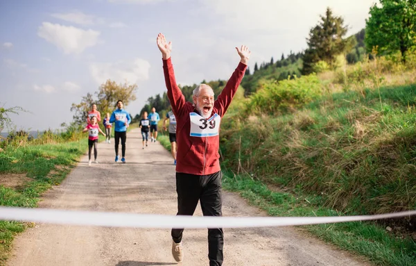 Старший чоловік бігун перетинає фінішну лінію в гоночному змаганні на природі . — стокове фото