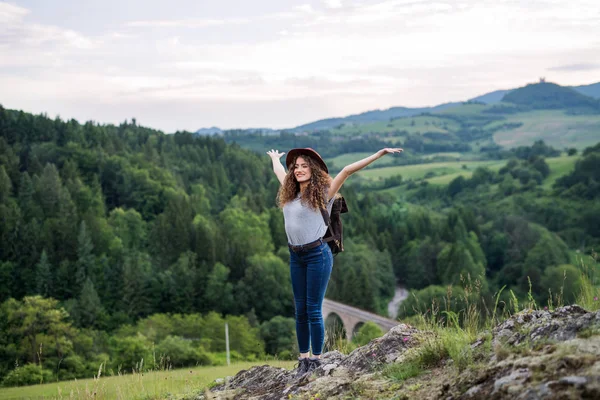 Junge Touristin mit Rucksack steht in der Natur und ruht sich aus. — Stockfoto