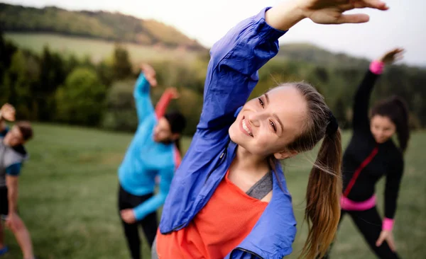 Grote groep van fit en actieve mensen doen oefening in de natuur, stretching. — Stockfoto