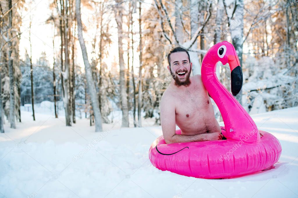 Topless young man outdoors in snow in winter forest, having fun.