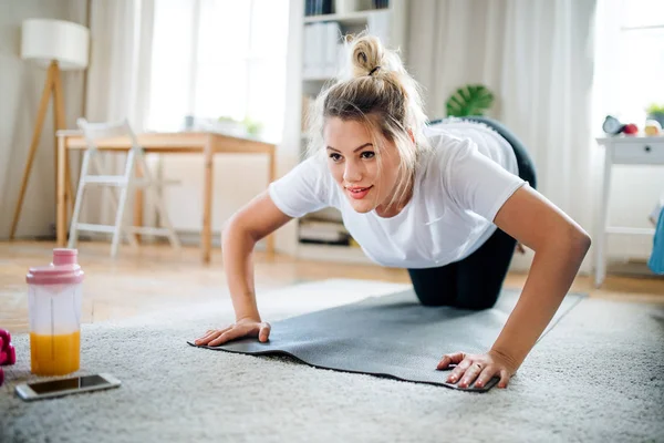 Jovem fazendo exercício no chão dentro de casa . — Fotografia de Stock