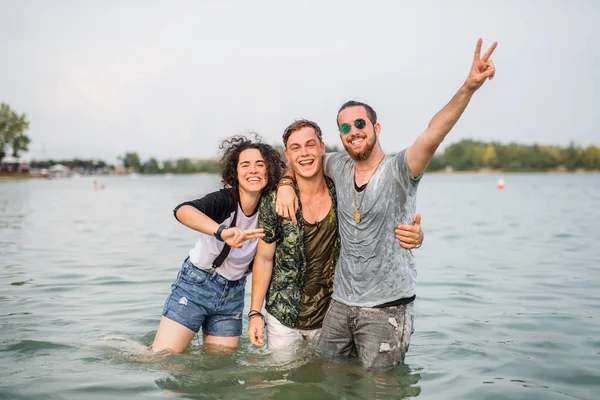 Grupo de jóvenes amigos en el festival de verano, de pie en el lago . — Foto de Stock