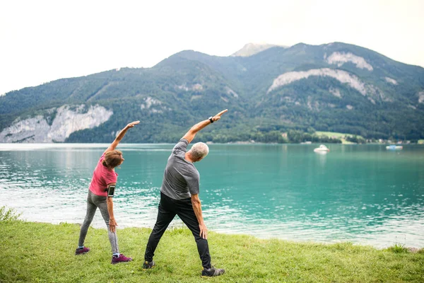 Vue arrière du couple de pensionnés âgés près du lac dans la nature, faisant de l'exercice . — Photo