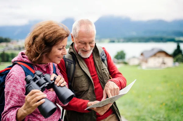 Coppia di pensionati anziani con escursioni nella natura, con binocolo e mappa . — Foto Stock