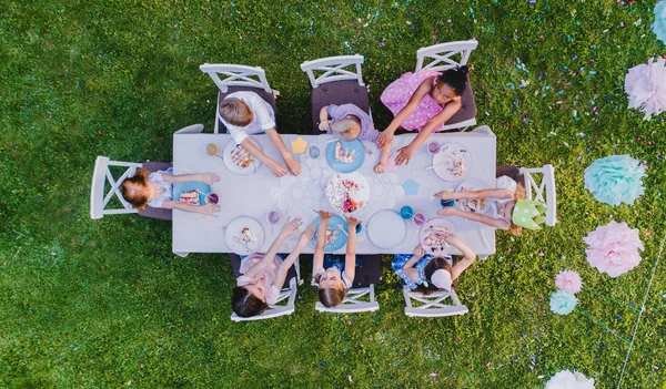 Vedere de sus a copiilor mici care stau la masă în aer liber la petrecerea în grădină . — Fotografie, imagine de stoc