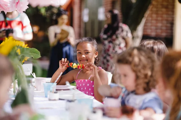 옥외 정원 파티 에서 식탁에 앉아 식사하는 어린아이들. — 스톡 사진