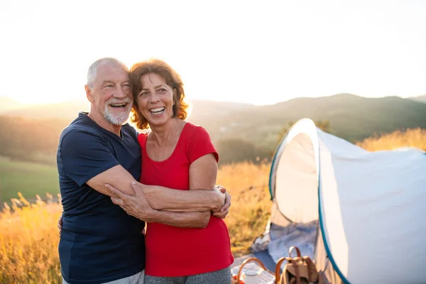 Senior tourist couple standing in nature at sunset, resting. — Stock Photo, Image