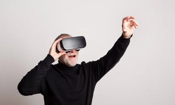 Portrait of a cheerful senior man with VR goggles in a studio. — Stock Photo, Image