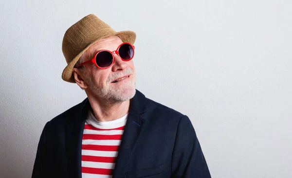 Retrato de un hombre mayor con gafas de sol rojas en un estudio . —  Fotos de Stock