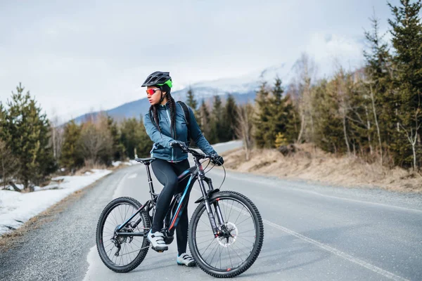 Kvinnlig mountainbikecyklist stående på väg utomhus i vinter natur. — Stockfoto