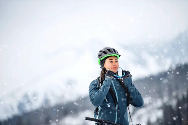 Жіночий гірський велосипедист з велосипедом, що стоїть на відкритому повітрі в зимовій природі . — стокове фото