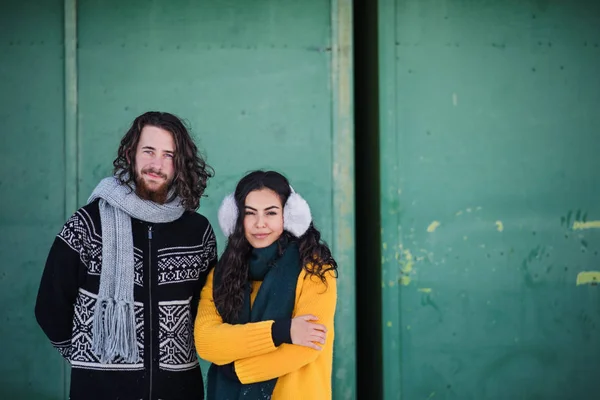 Un portrait de couple debout à l'extérieur en hiver, regardant la caméra . — Photo