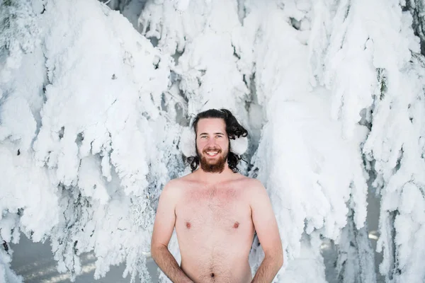 Oben ohne junger Mann im Schnee im winterlichen Wald und blickt in die Kamera. — Stockfoto