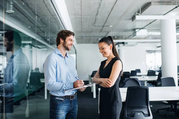 Young businesspeople with clipboard in an office, working. — Stock Photo, Image