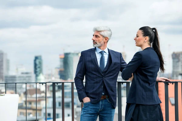 Ein Geschäftsmann und eine Geschäftsfrau stehen auf einer Terrasse und reden. — Stockfoto