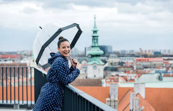 Eine junge Frau mit Regenschirm steht auf einer Terrasse und ruht sich aus. — Stockfoto