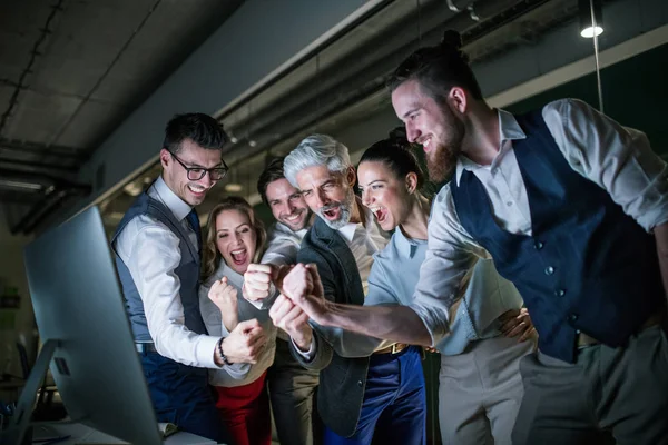 Een groep van zakenmensen met een computer in een kantoor, het uiten van opwinding. — Stockfoto