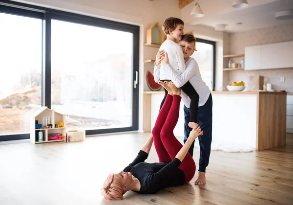 Una giovane donna con due bambini che giocano sul pavimento, divertendosi . — Foto Stock