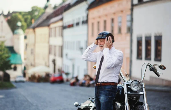 町にバイクを持つ高級ビジネスマンヘルメットをかぶって. — ストック写真