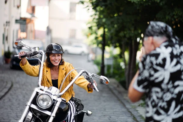 Wesoła para starszych podróżnych z motocyklem w mieście, robienie zdjęć. — Zdjęcie stockowe