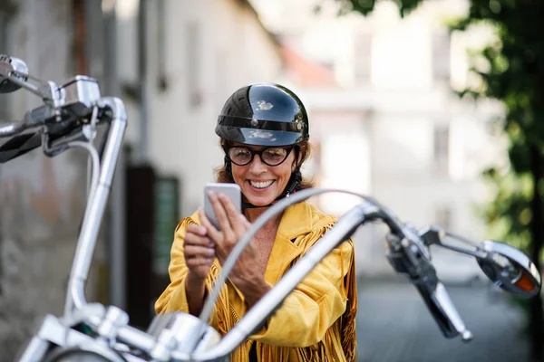 Mulher idosa alegre viajante com moto na cidade, tirando selfie . — Fotografia de Stock