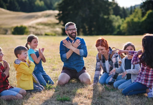 Group of school children with teacher on field trip in nature, chanting. — Stock Photo, Image