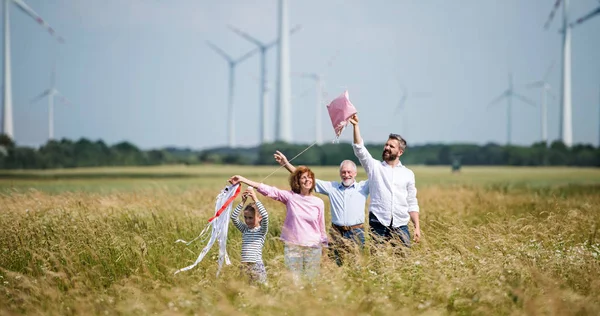 多代家庭站在风电场上放风筝. — 图库照片