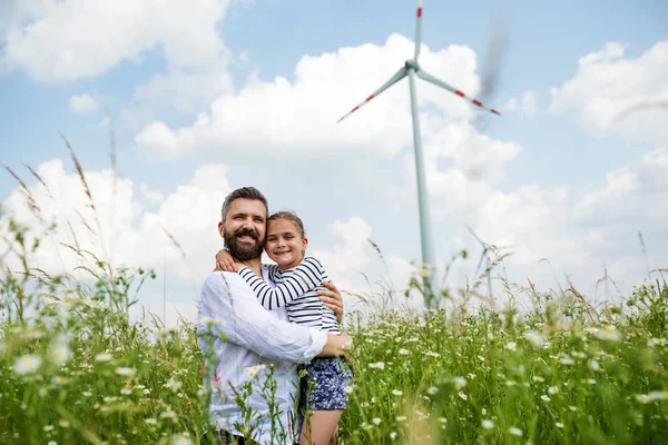 Dojrzały father z mały córka stojący na pole na farma wiatrowa. — Zdjęcie stockowe