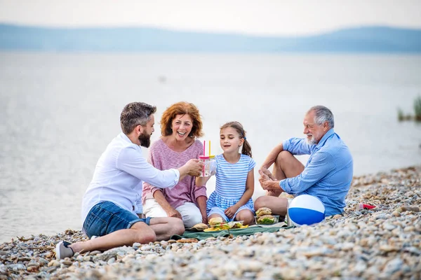 Rodina multigenerace na dovolenou u jezera, piknik. — Stock fotografie