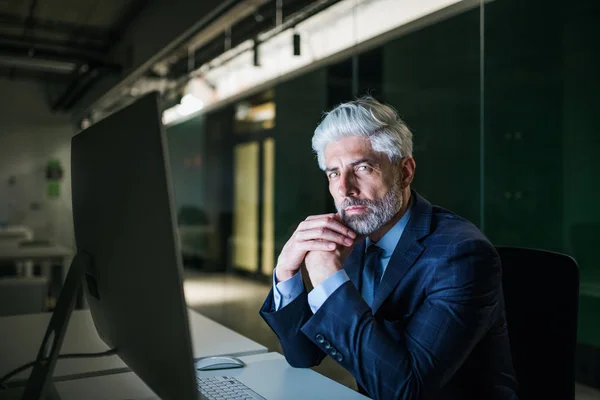 Ritratto di uomo d'affari maturo con computer in un ufficio, guardando la macchina fotografica . — Foto Stock