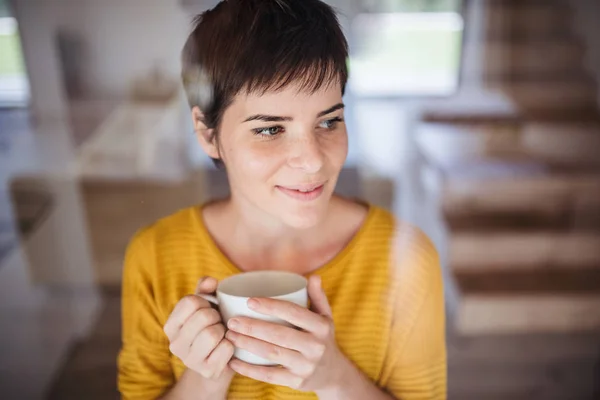 Vista frontal de mujer joven con café de pie en el interior de su casa . —  Fotos de Stock