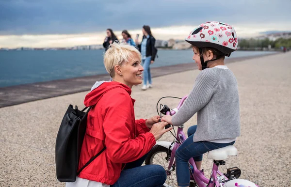 Mãe e filha pequena com bicicleta ao ar livre na praia, falando . — Fotografia de Stock