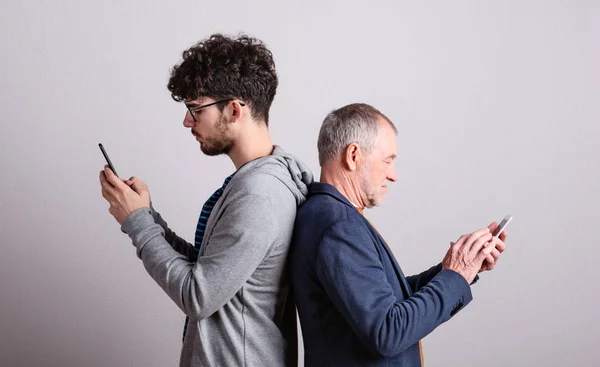 Προσωπογραφία ενός πατέρα και ενός γιου σε ένα στούντιο, χρησιμοποιώντας smartphones. — Φωτογραφία Αρχείου