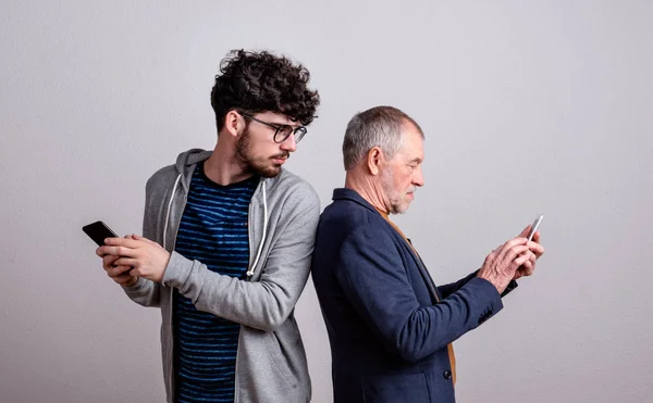 Ritratto di padre anziano e figlio in studio, con smartphone . — Foto Stock