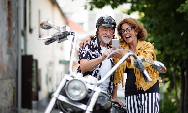 Wesoła para starszych podróżnych z motocyklem w mieście, robienie selfie. — Zdjęcie stockowe