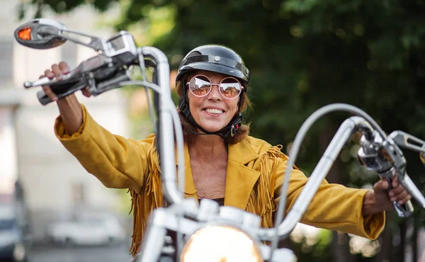 Wesoły starszy kobieta podróżnik z motocyklem w mieście. — Zdjęcie stockowe