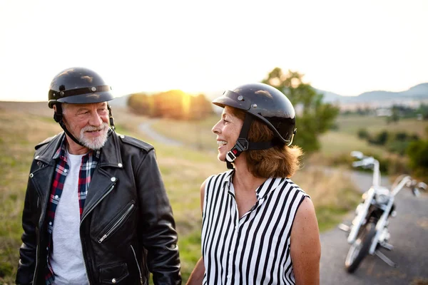 Una alegre pareja de viajeros mayores con moto en el campo . —  Fotos de Stock