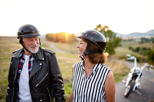 Wesoła para starszych podróżnych z motocyklem na wsi. — Zdjęcie stockowe