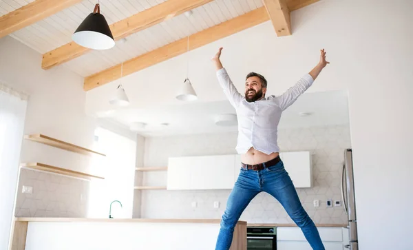 Glada mogna mannen flyttar in i nya omöblerade hus, hoppar. — Stockfoto
