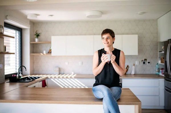 Front view of young woman with coffee sitting indoors at home. — Stock Photo, Image