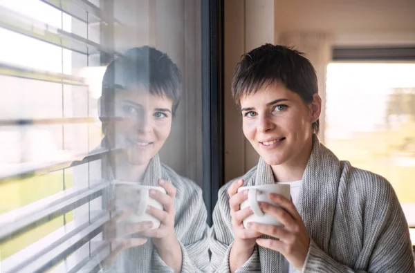 Retrato de mujer joven con café de pie en el interior por la ventana en casa . — Foto de Stock