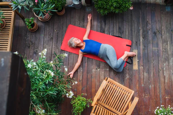 En utsikt över äldre kvinna utomhus på en terrass på sommaren, gör motion. — Stockfoto