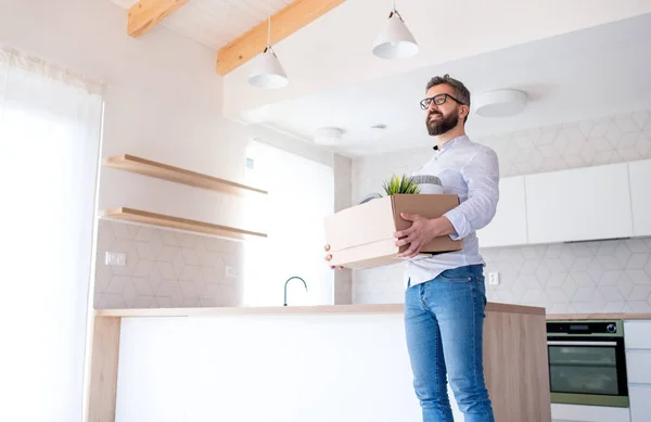 Low angle view of mature man with box moving in new unfurnished house. — Stock Photo, Image