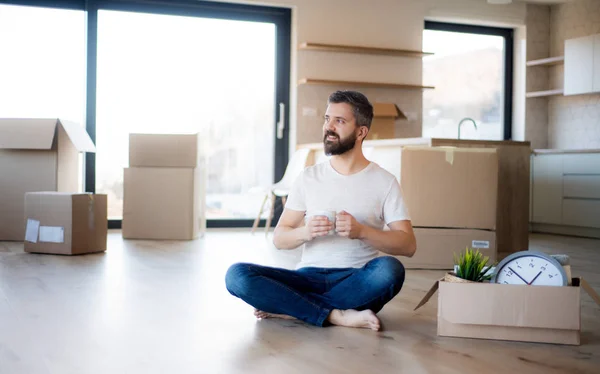 Mature man with coffee and boxes moving in new house, unpacking. — 图库照片