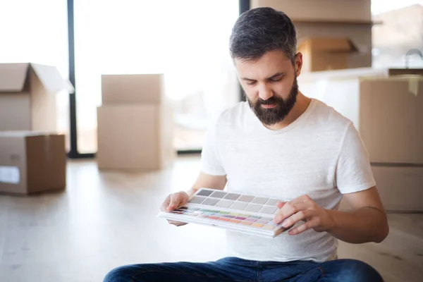 Mature man with boxes moving in new house, looking at color swatch. — ストック写真