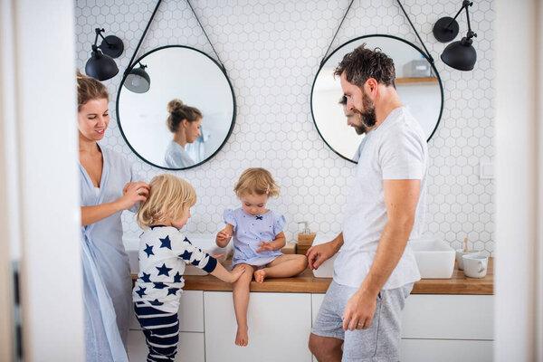 Young family with two small children indoors in bathroom, talking.