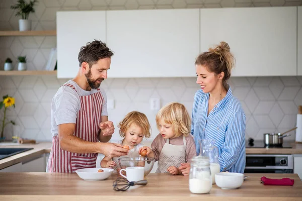 Mutfakta iki küçük çocuğu olan genç bir aile yemek pişiriyor.. — Stok fotoğraf