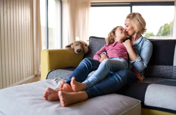 En söt liten flicka med mamma på soffan inomhus, vilande. — Stockfoto